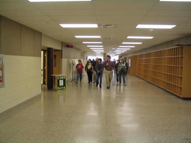 Looking down the hall into what used to be the cafeteria.  Classrooms & lavs were built on the left side, cubbies on the right are where students store their books during lunch.  The small auditorium is behind the wall of cubbies.