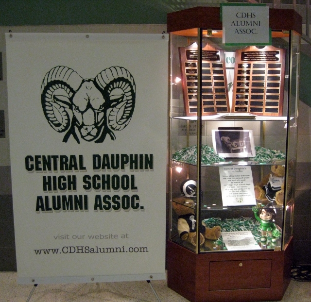Our display case in the CDHS aud/gym lobby.  The Alumnus of the Year perpetual plaque is on the top shelf, along with the School Spirit Scholarship plaque.